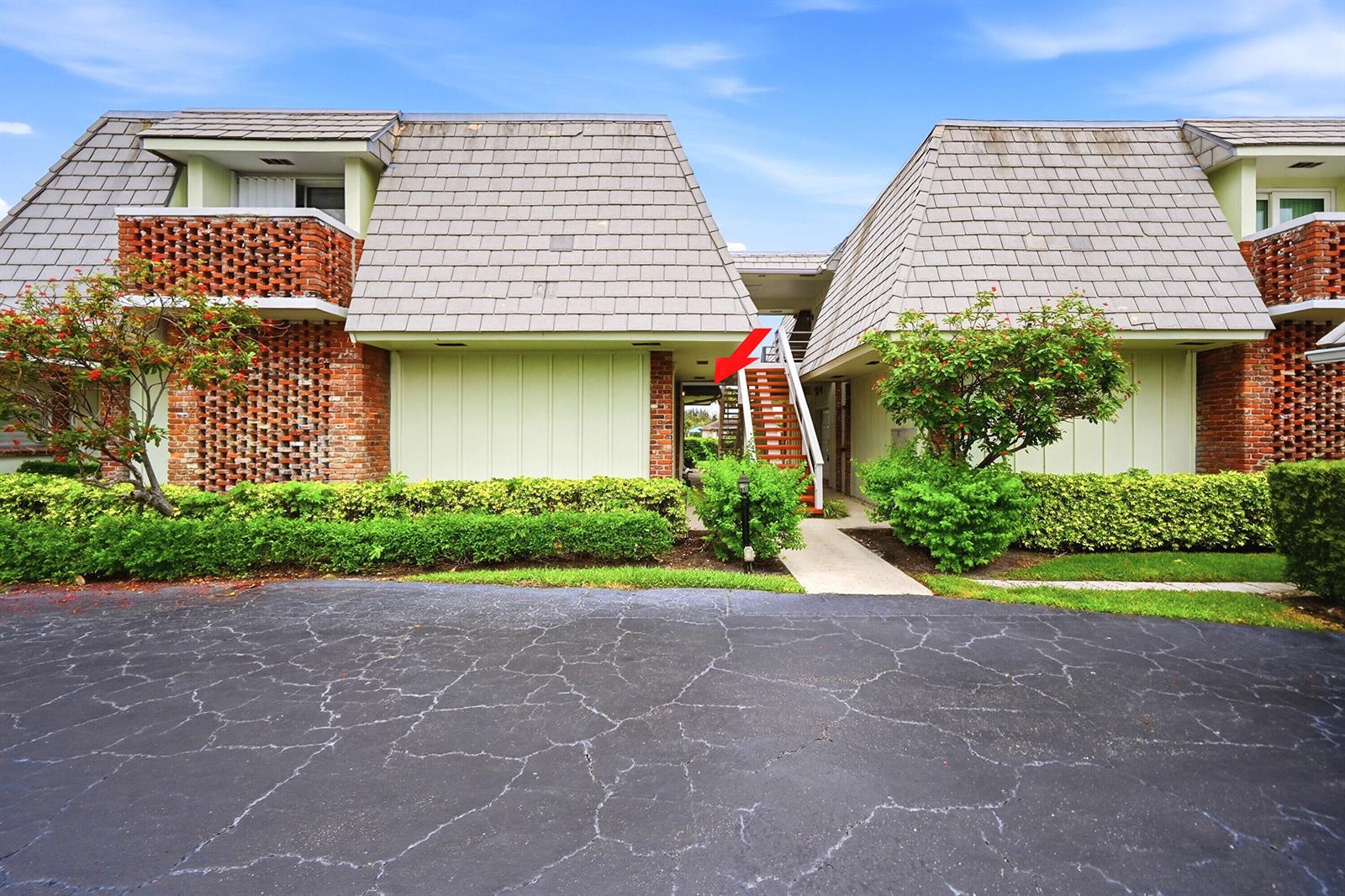 Exterior view of a two-story apartment building with brick accents and a central staircase — 324 Orange Tree Drive # 4, Atlantis FL 33462, ATLANTIS, FL