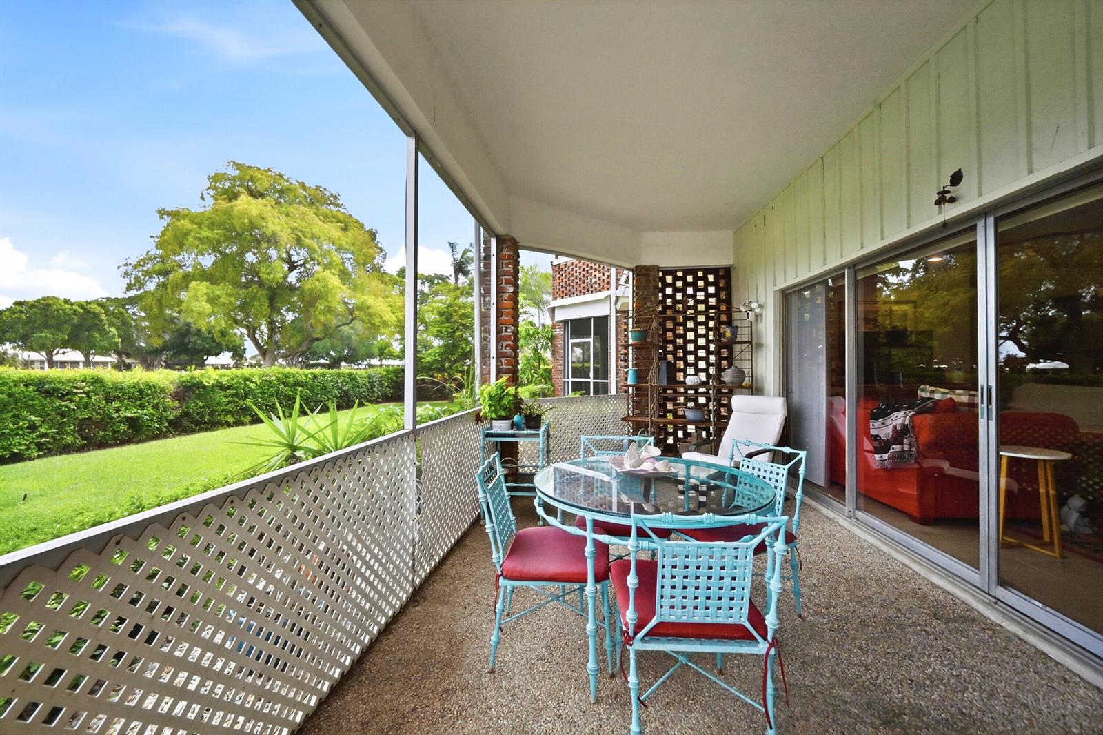 A screened-in patio features a glass dining table, metal chairs, and views of a sunset — 324 Orange Tree Drive # 4, Atlantis FL 33462, ATLANTIS, FL