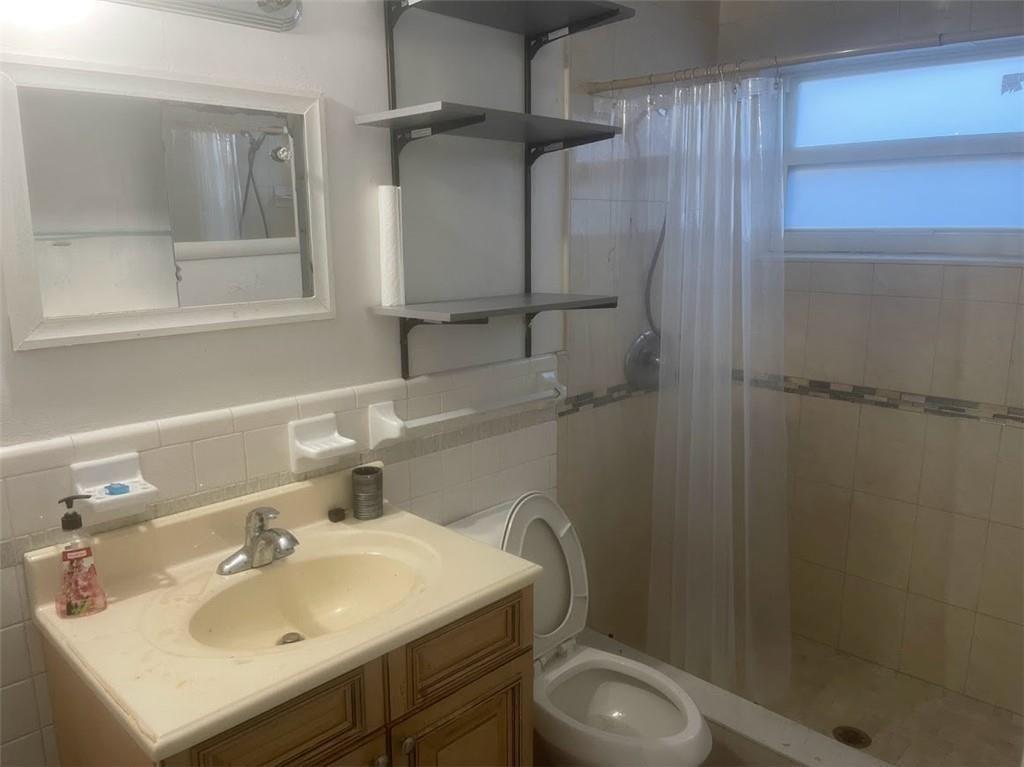 A bathroom features a vanity with a sink, a toilet, and a shower with curtains — SUNRISE, FL