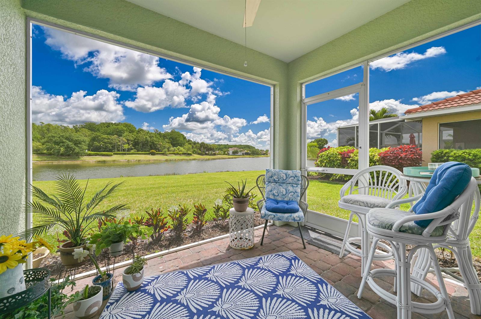 A screened-in patio features brick flooring, wicker furniture, and a view of a lake — 2877 Apple Blossom Drive, FL 33920, FL