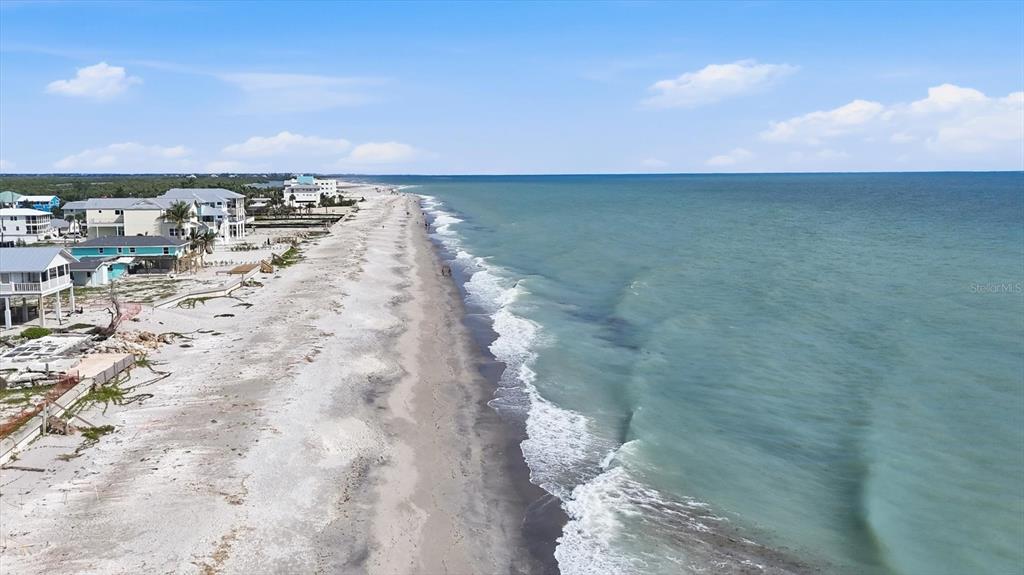 An aerial view shows a sandy beach shoreline with several houses along the coast — 1245 SHORE VIEW DRIVE, ENGLEWOOD, FL