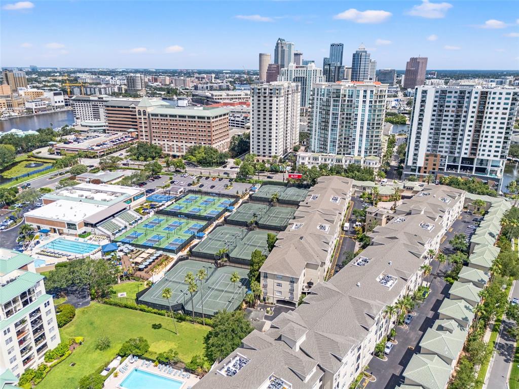 Aerial view of a residential complex with tennis courts and a pool near a city — 501 KNIGHTS RUN AVENUE UNIT 2111, TAMPA, FL