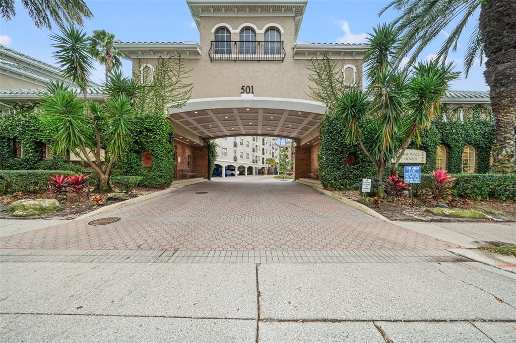 A paved driveway leads through a covered entrance archway to a multi-story apartment building — 501 KNIGHTS RUN AVENUE UNIT 2111, TAMPA, FL