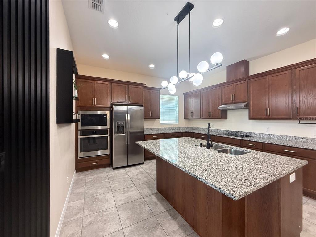 A kitchen features dark wood cabinets, granite countertops, stainless steel appliances, and a central island — 2074 BRILLANTE DRIVE, ST CLOUD, FL