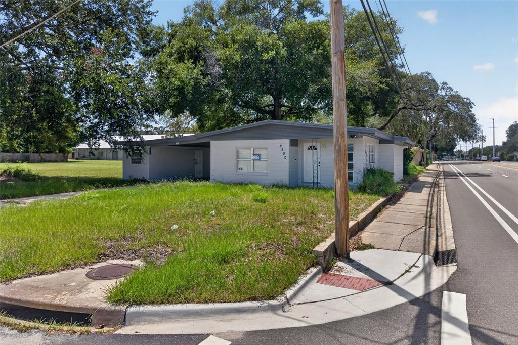 A single-story white house with a gray roof and attached carport sits on a corner lot — 2500 MYRTLE AVENUE, SANFORD, FL