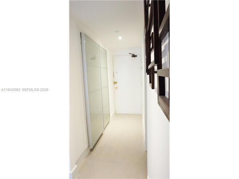 A narrow hallway features a white door, light tile flooring, and a large glass-paneled closet — 100 Lincoln Rd # 420, Miami Beach FL 33139, MIAMI BEACH, FL