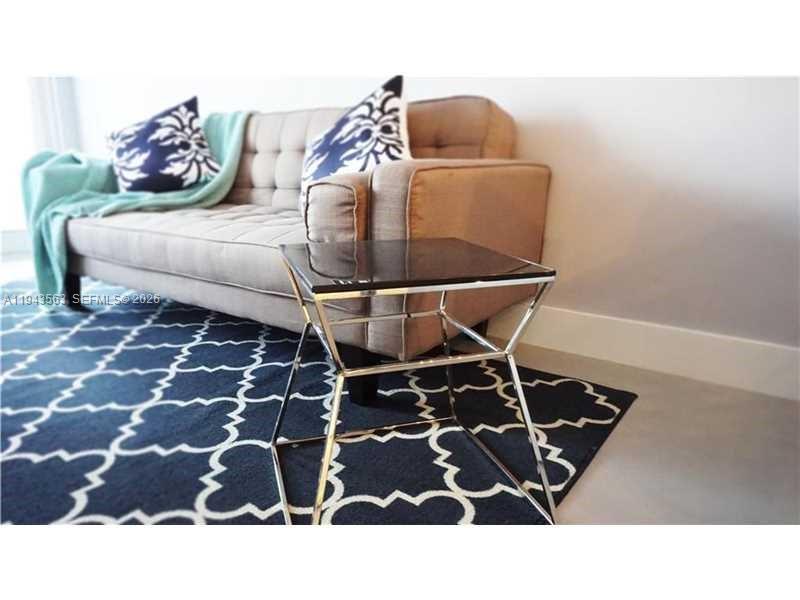A beige tufted sofa with patterned pillows sits on a blue and white rug — 100 Lincoln Rd # 420, Miami Beach FL 33139, MIAMI BEACH, FL