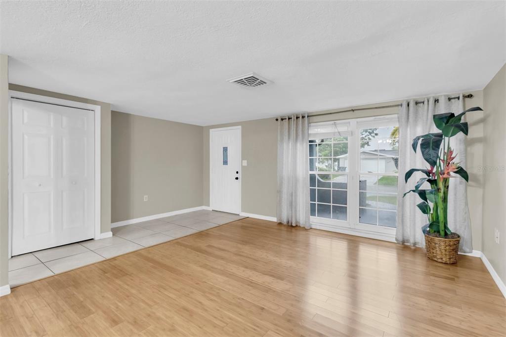 A living room features light wood flooring, a tiled entryway, a white door, and windows — 9203 GREENBRIAR LANE, PORT RICHEY, FL