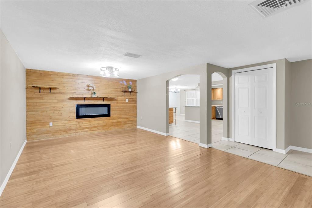 A living room features light wood flooring, a wood-paneled accent wall, and a built-in fireplace — 9203 GREENBRIAR LANE, PORT RICHEY, FL