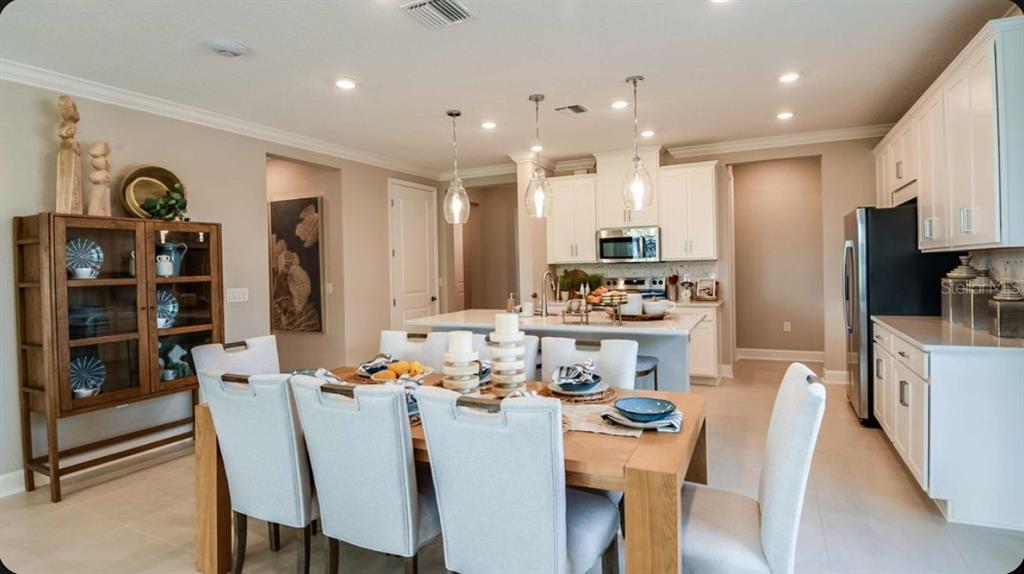 A dining area with a wooden table and chairs sits adjacent to a white kitchen — 23 GEOSAM DRIVE, PALM COAST, FL