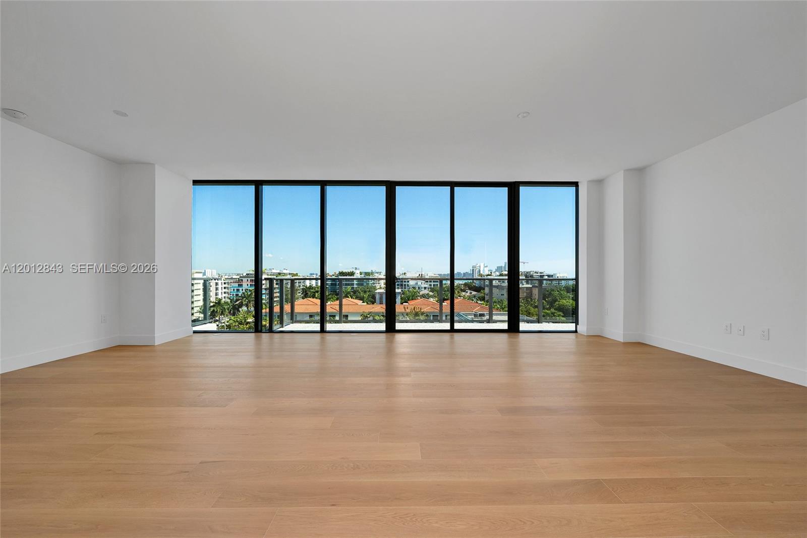 A modern living room features floor-to-ceiling windows, light wood flooring, and a neutral sectional sofa — 1176 97th St # 809, Bay Harbor Islands FL 33154, BAY HARBOR ISLANDS, FL