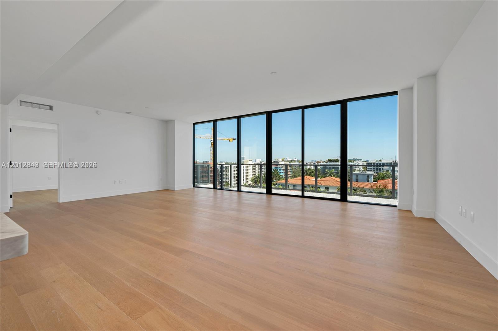 A modern open-concept living room and kitchen featuring light wood floors and neutral furniture — 1176 97th St # 809, Bay Harbor Islands FL 33154, BAY HARBOR ISLANDS, FL