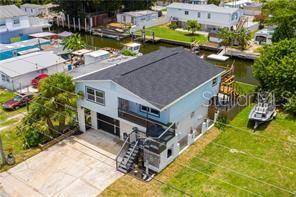 An aerial view shows a two-story house with a dark roof near a canal — 6728 SEA RANCH DR, HUDSON, FL