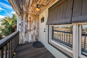 A wooden balcony features a nautical anchor wall decoration, a light fixture, and a door — 6728 SEA RANCH DR, HUDSON, FL
