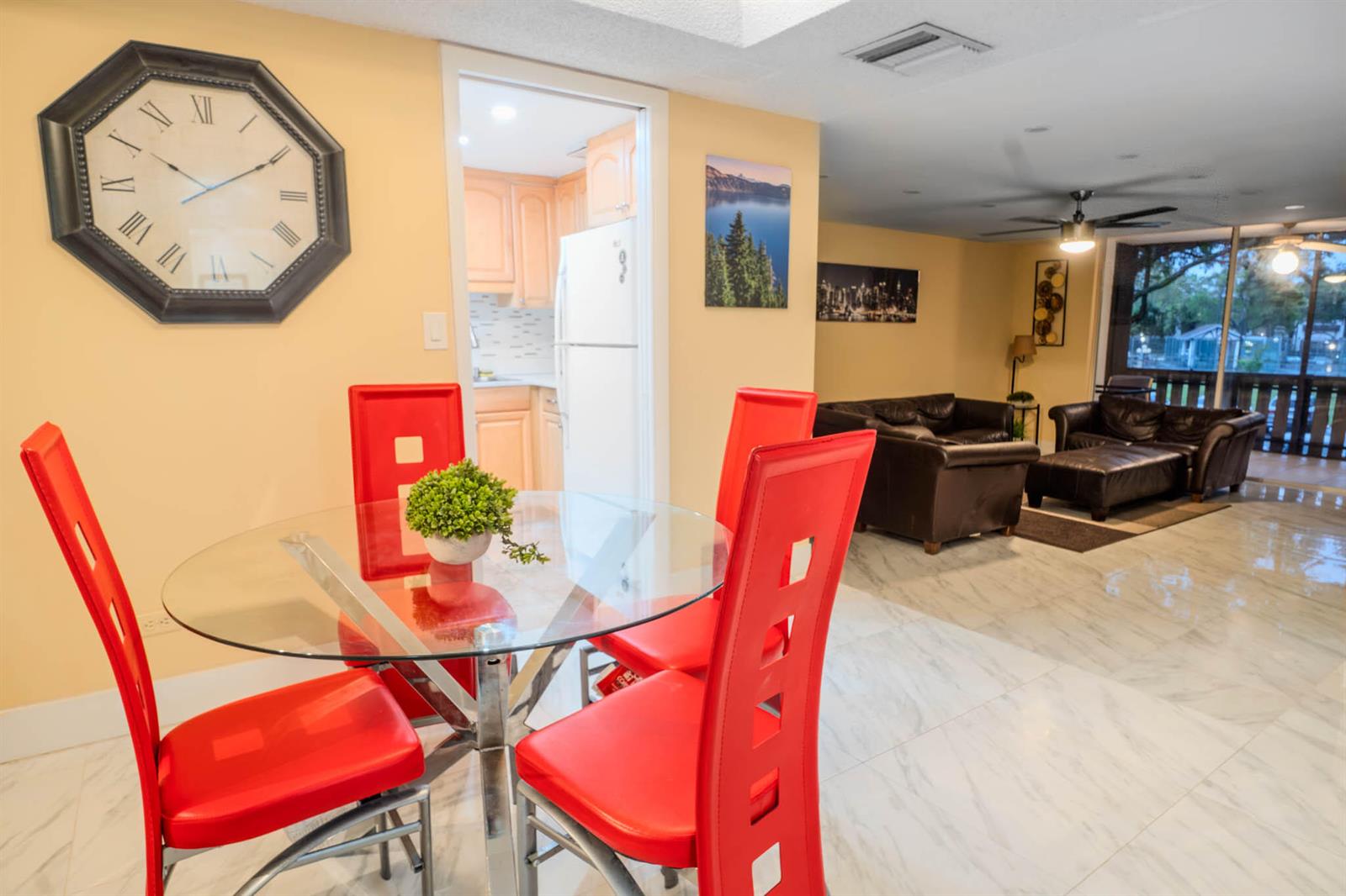 A dining area with a glass table and red chairs opens into a living room — 3710 Inverrary Drive # 2s, Lauderhill FL 33319, LAUDERHILL, FL