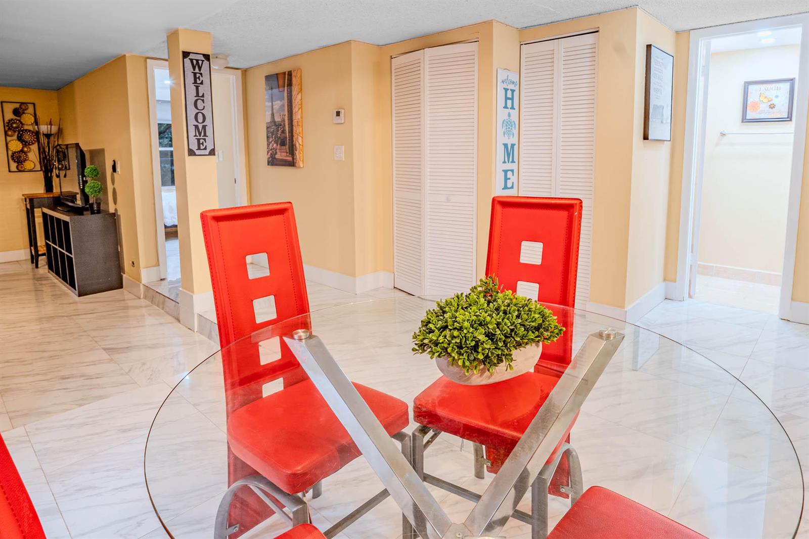 A dining area features a glass table with red chairs on a white tiled floor — 3710 Inverrary Drive # 2s, Lauderhill FL 33319, LAUDERHILL, FL