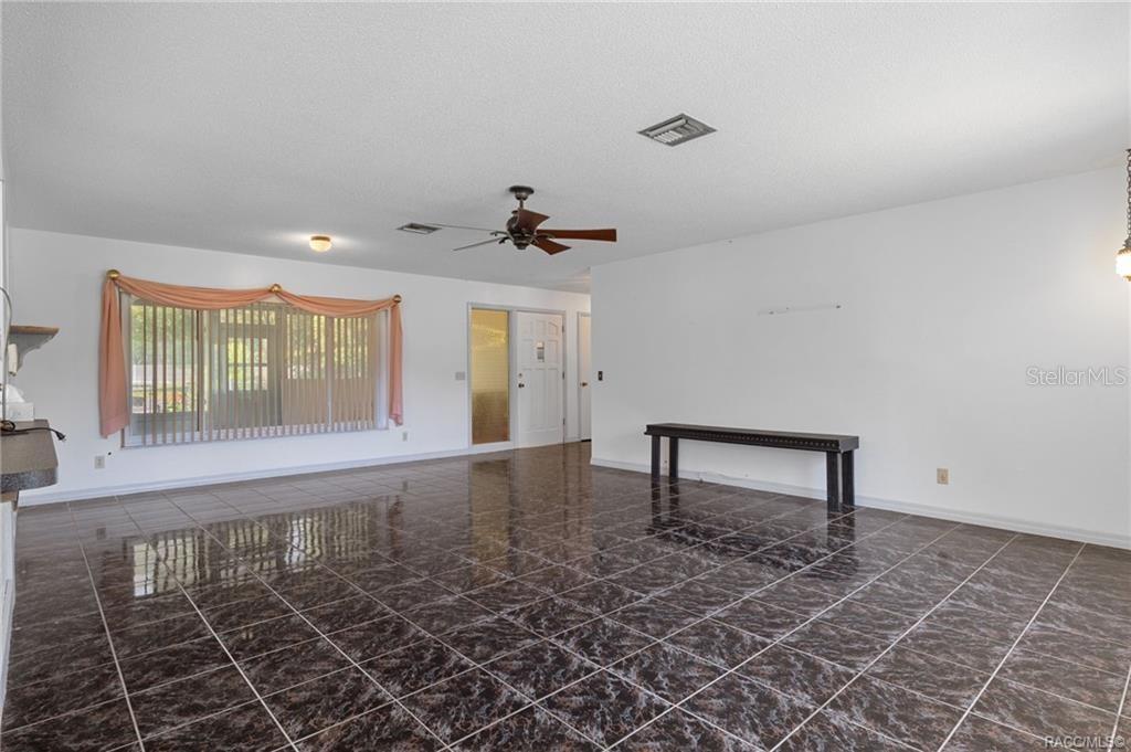 A spacious room with dark marble-patterned tile flooring, a ceiling fan, and a large window — 7251 W LACEY LANE, HOMOSASSA, FL