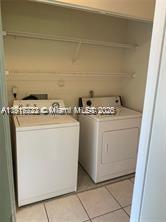 A laundry closet contains a white washing machine and a white dryer beneath shelving — 1314 White Pine Dr # B, Wellington FL 33414, WELLINGTON, FL