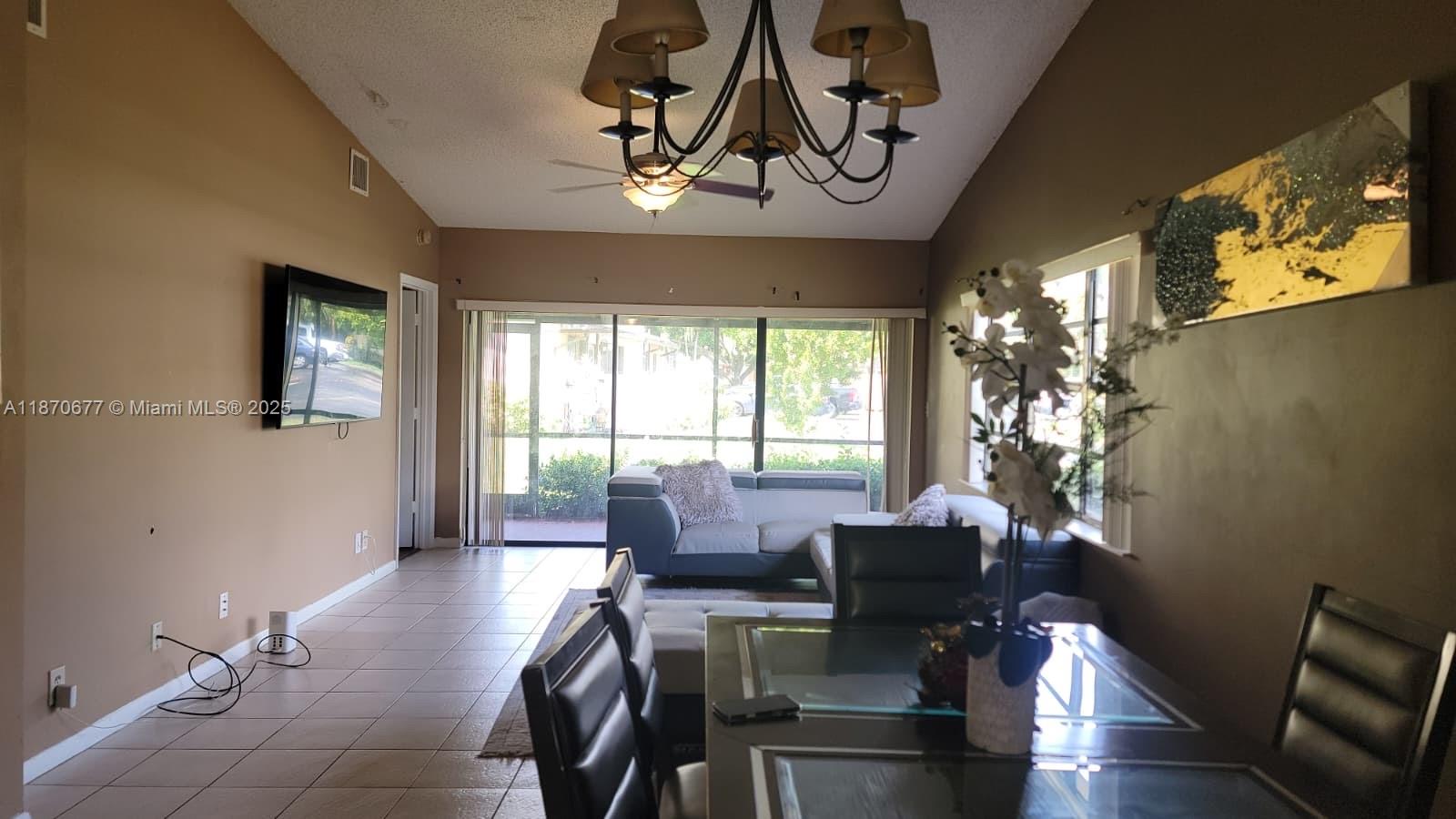 A living and dining area features tile floors, a chandelier, and sliding glass patio doors — 715 Banks Rd, Margate FL 33063, MARGATE, FL