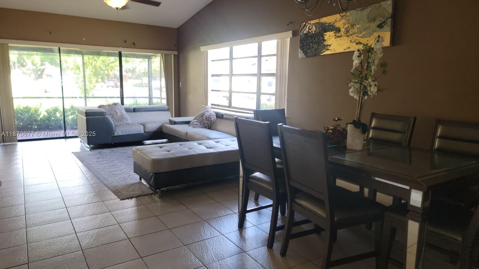 An open-concept living and dining area features tile floors, a sectional sofa, and a table — 715 Banks Rd, Margate FL 33063, MARGATE, FL