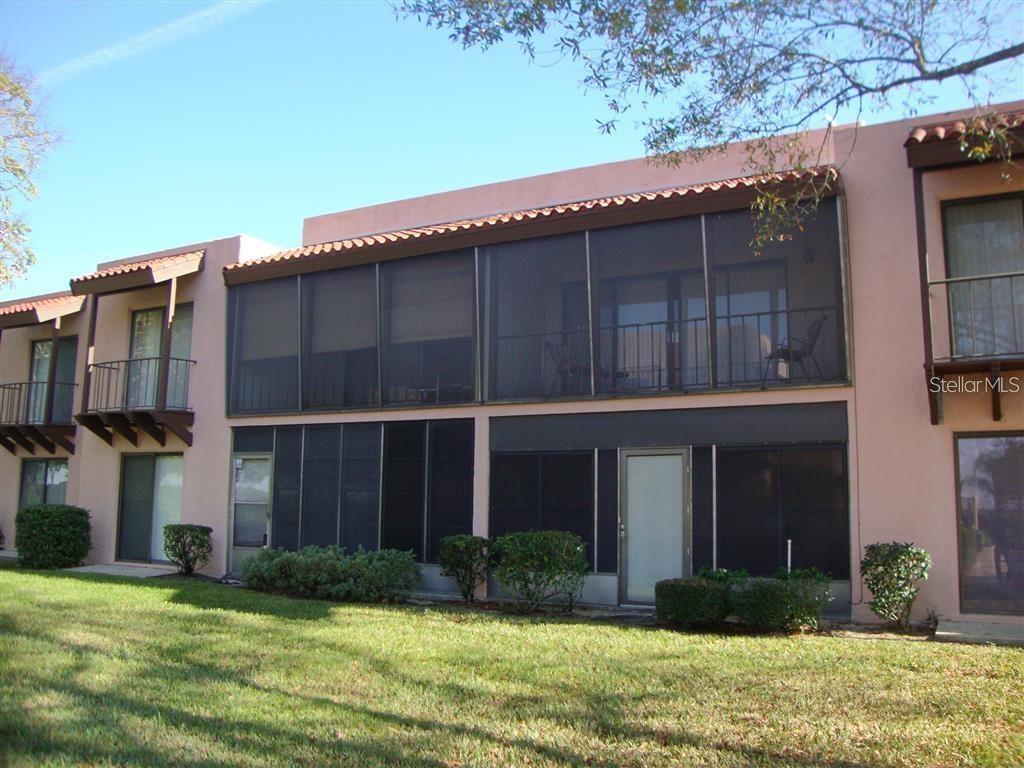 A two-story building with pink stucco walls, screened-in balconies, and a grassy lawn — 215 LA CASA UNIT 215, LAKE WALES, FL
