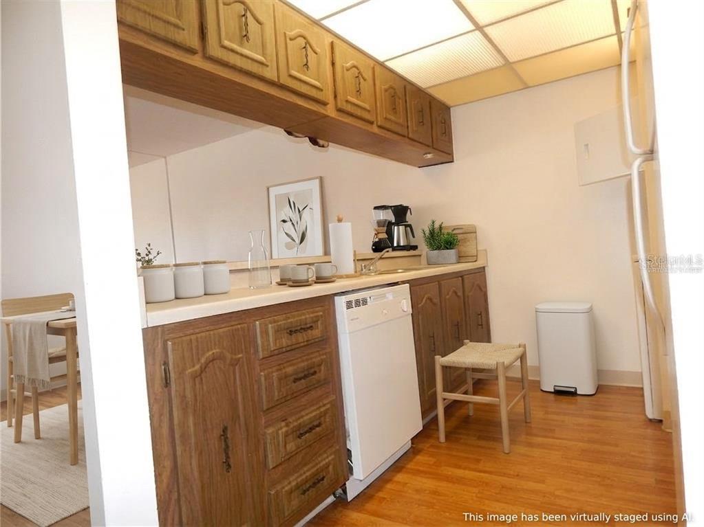 A kitchen features wood cabinets, a white dishwasher, and a drop ceiling with recessed lighting — 215 LA CASA UNIT 215, LAKE WALES, FL
