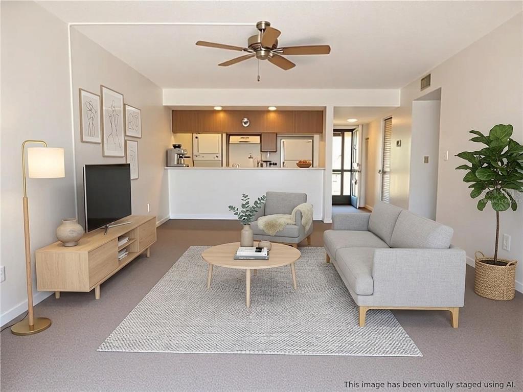 This virtually staged living room features a grey sofa, armchair, coffee table, and television console — 215 LA CASA UNIT 215, LAKE WALES, FL