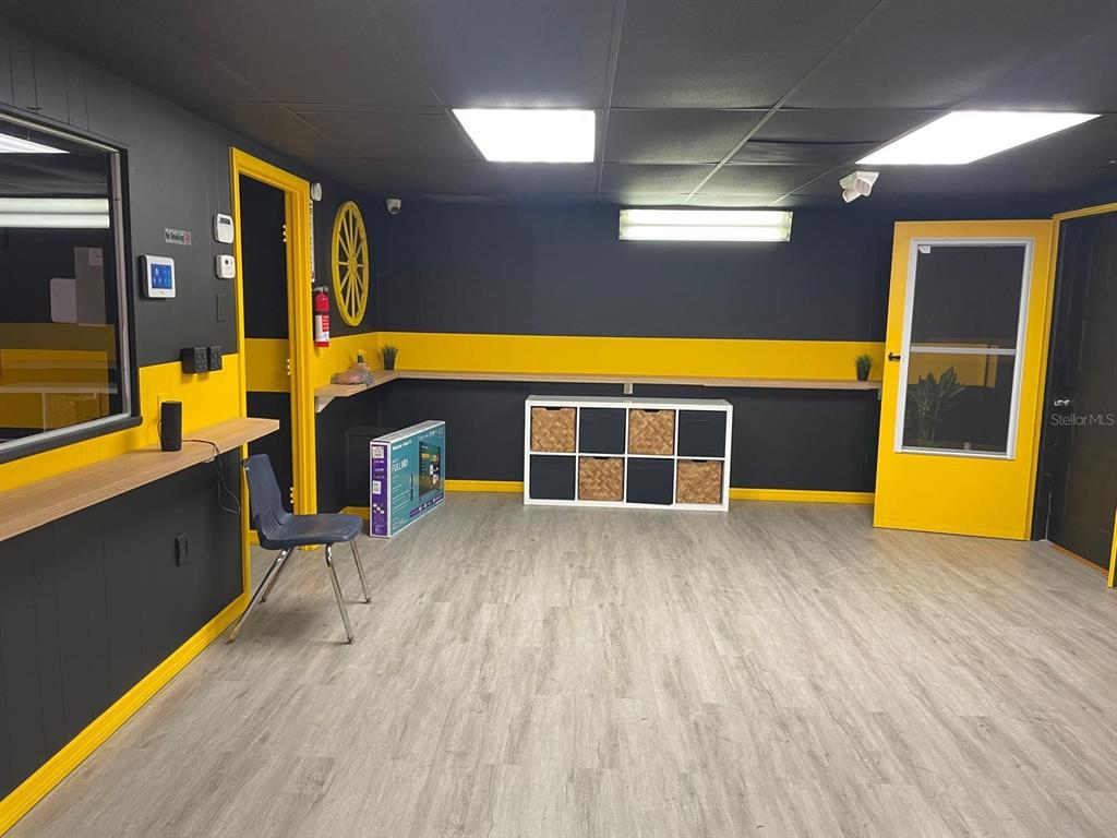 A room with black walls, yellow trim, light wood flooring, and a white storage unit — 1210-1232 DYER BOULEVARD UNIT 1214, KISSIMMEE, FL
