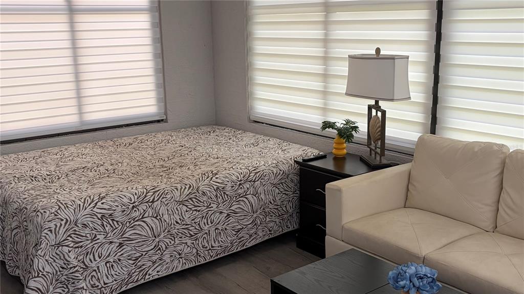 A bedroom features a bed with a patterned cover, a nightstand, and a beige sofa — 389 NOLANE LANE, POLK CITY, FL