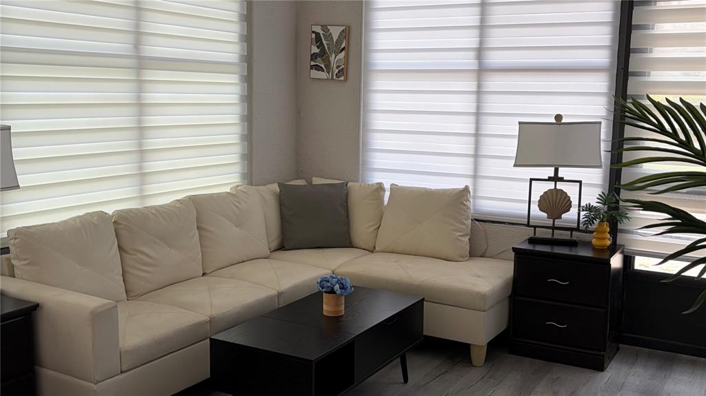 A living room features a cream-colored sectional sofa, a black coffee table, and window blinds — 389 NOLANE LANE, POLK CITY, FL