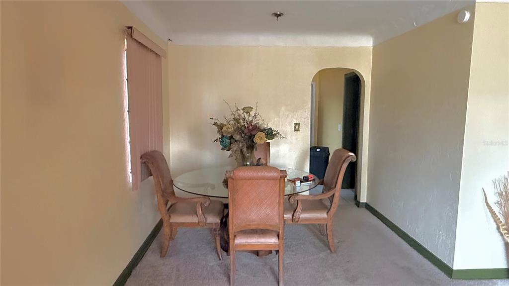 A dining room features a glass table with three chairs, beige walls, and carpeted flooring — 2055 29TH STREET S, ST PETERSBURG, FL