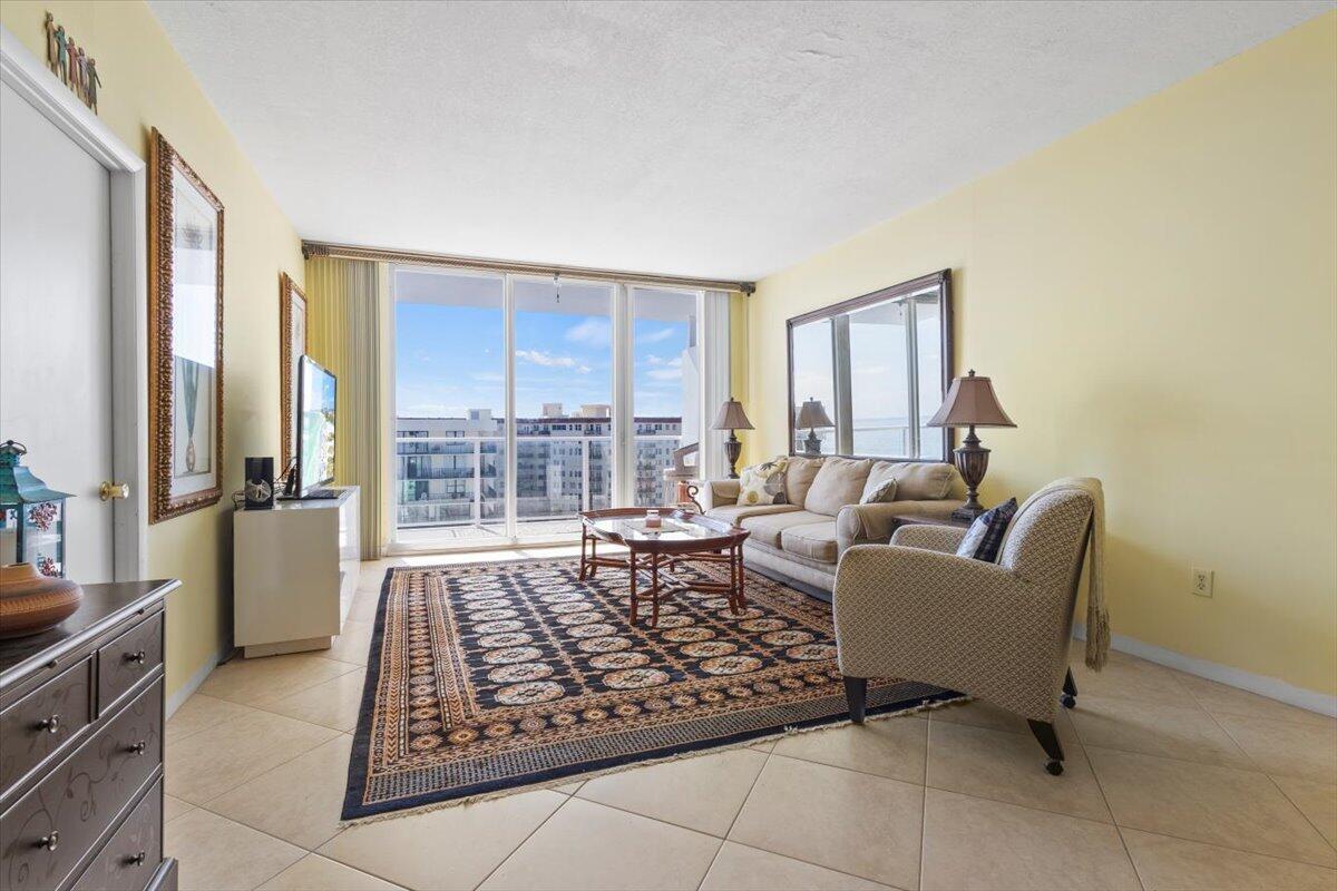 A living room features a patterned area rug, beige sofa, armchair, and floor-to-ceiling balcony windows — 3450 S Ocean Boulevard # 8120, Palm Beach FL 33480, PALM BEACH, FL