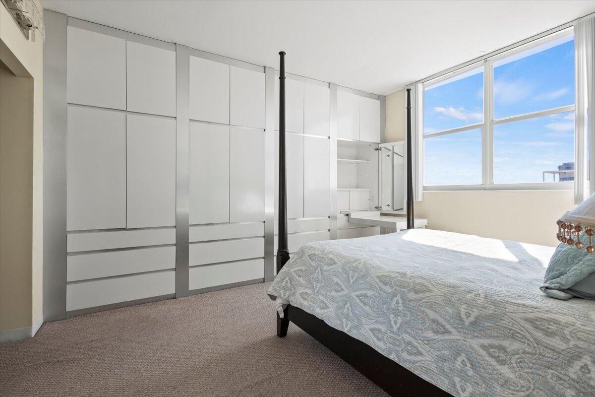 A bedroom features a large white wall-to-wall wardrobe, a four-poster bed, and a large window — 3450 S Ocean Boulevard # 8120, Palm Beach FL 33480, PALM BEACH, FL