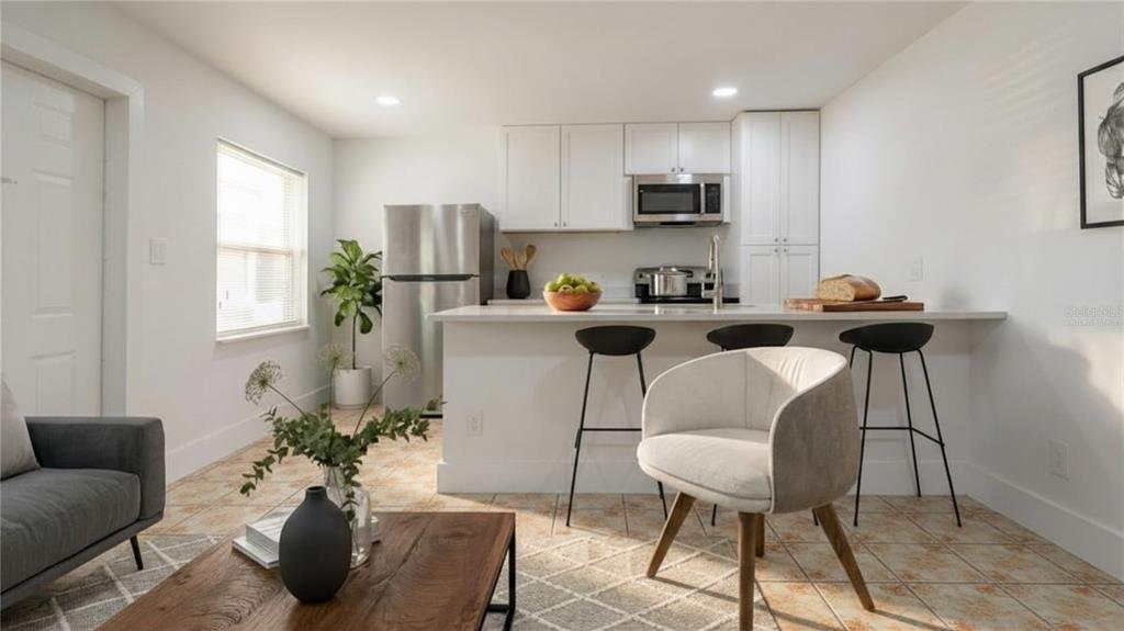 A kitchen with white cabinets, stainless steel appliances, and a breakfast bar with three stools — 3017 49TH STREET S UNIT 5, GULFPORT, FL