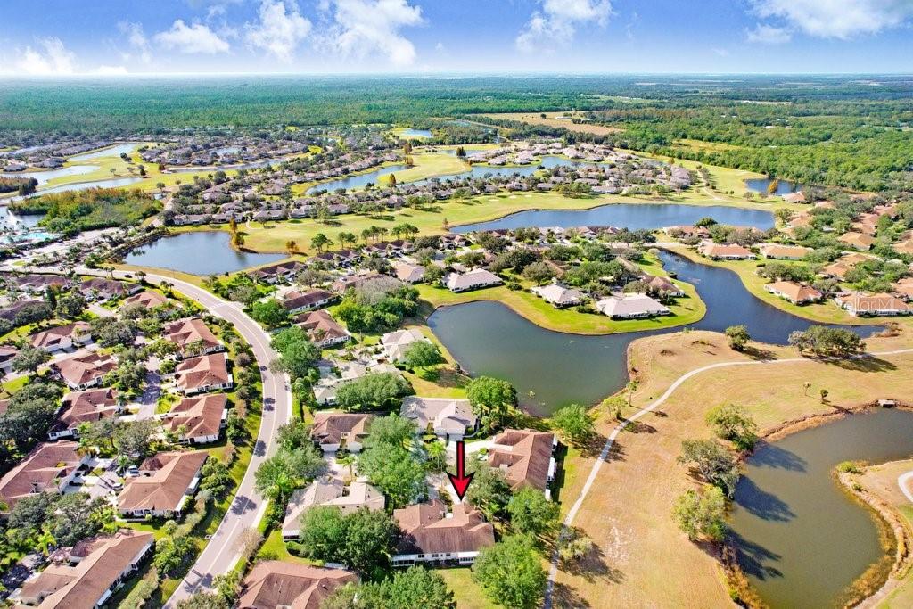 An aerial view shows a residential house with a red arrow pointing to its roof — 2608 NEWCOMB COURT UNIT 2608, SUN CITY CENTER, FL