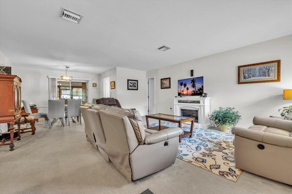 A living room features beige carpet, a fireplace with a television, and neutral furniture — 4085 DRANCE STREET, PUNTA GORDA, FL
