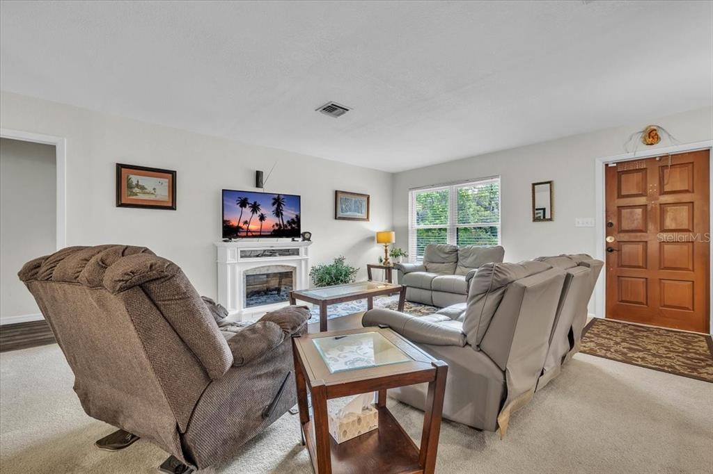 A living room features a fireplace, a television, two sofas, and a wooden front door — 4085 DRANCE STREET, PUNTA GORDA, FL