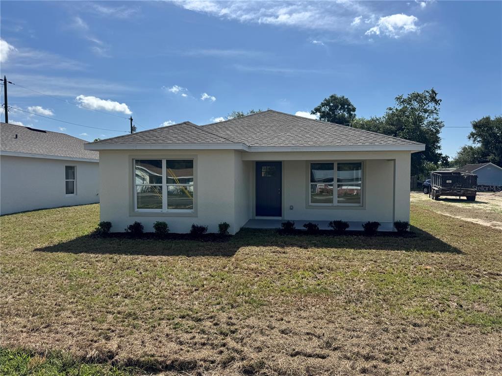 A single-story house with a light-colored stucco exterior and a dark gray shingled roof — 6020 12TH STREET, ZEPHYRHILLS, FL