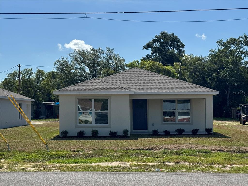 A single-story, light-colored stucco house with a dark front door and a hip roof — 6020 12TH STREET, ZEPHYRHILLS, FL