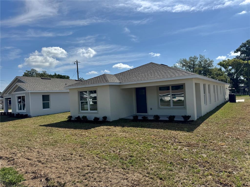 A single-story, light-colored house with a hip roof sits on a grassy lot — 6020 12TH STREET, ZEPHYRHILLS, FL