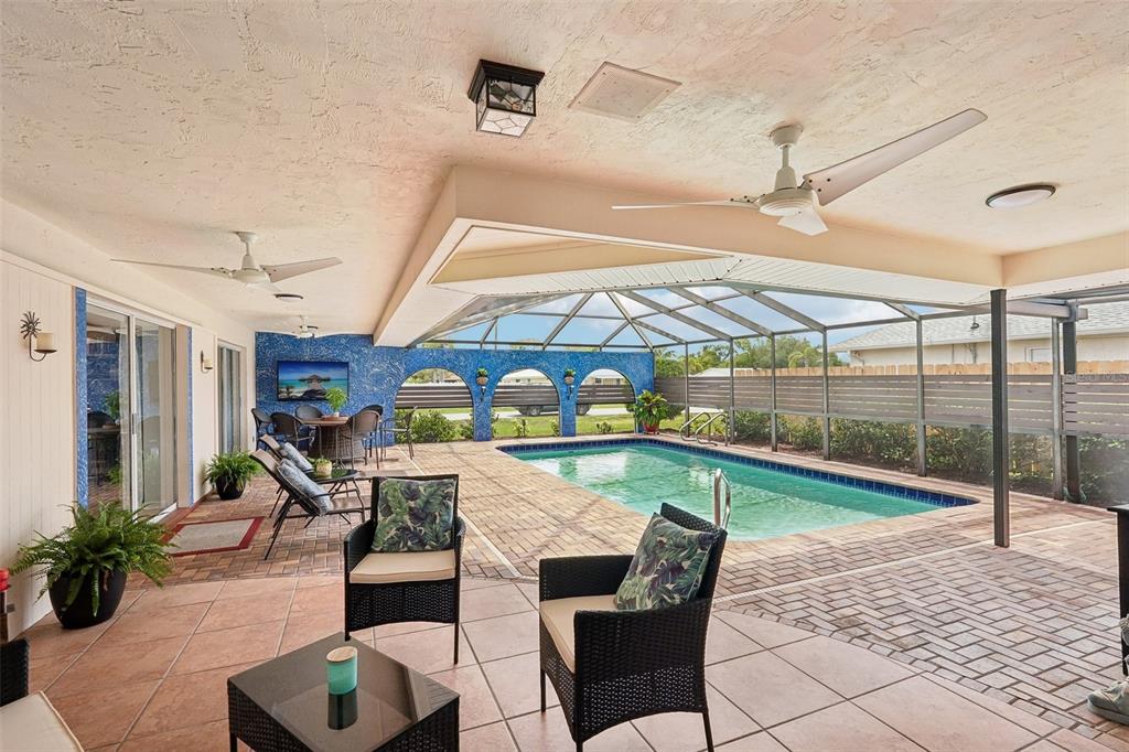 A covered patio features a swimming pool, tiled flooring, and a blue mosaic accent wall — 1201 JAMAICA ROAD, VENICE, FL