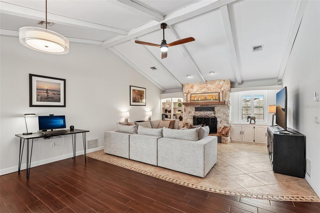 A living room features a stone fireplace, vaulted beamed ceilings, and a mix of flooring — 1201 JAMAICA ROAD, VENICE, FL
