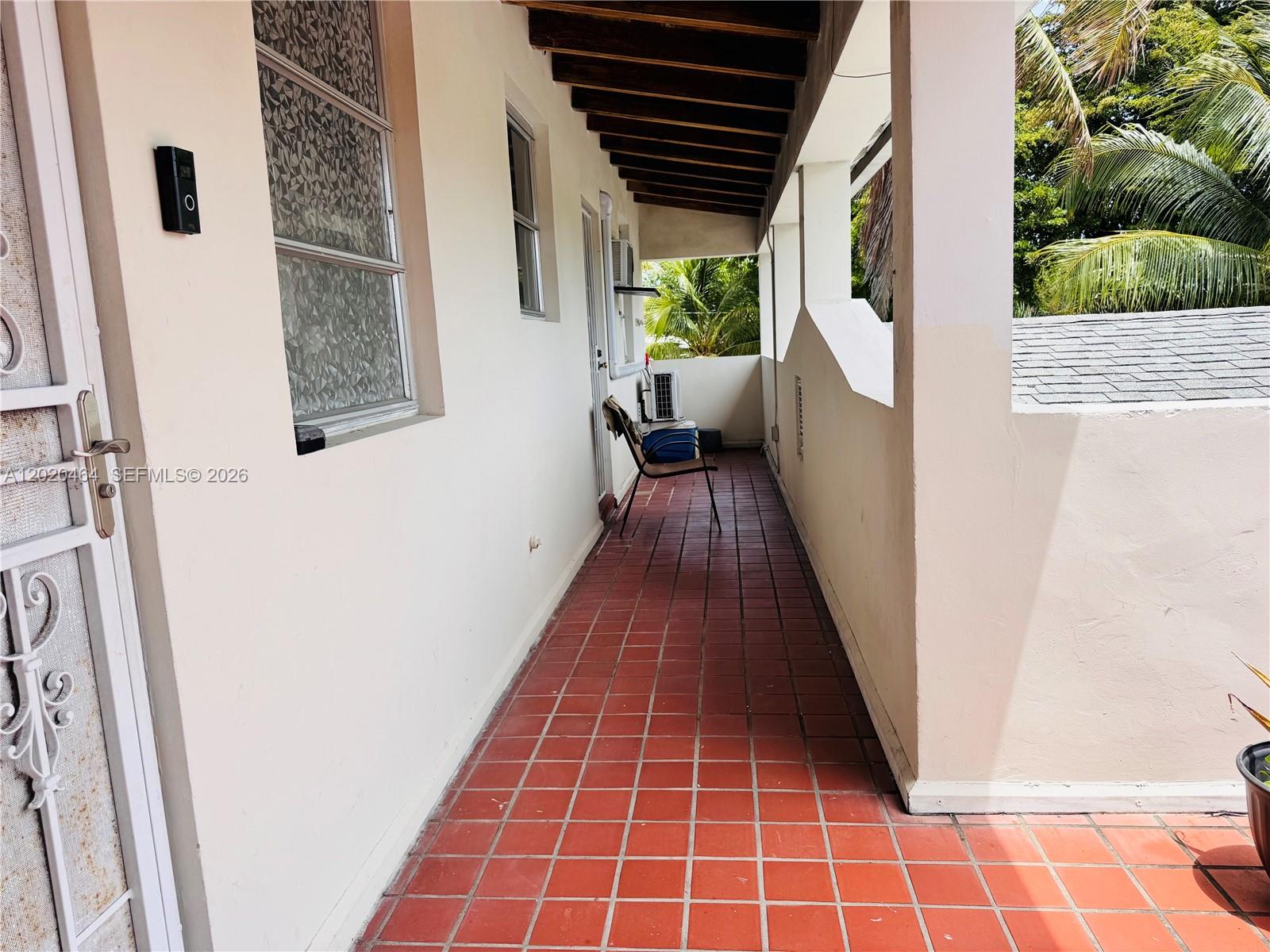 A covered outdoor balcony features red tile flooring, a single chair, and white walls — 756 N 17th Ave # 15, Hollywood FL 33020, HOLLYWOOD, FL