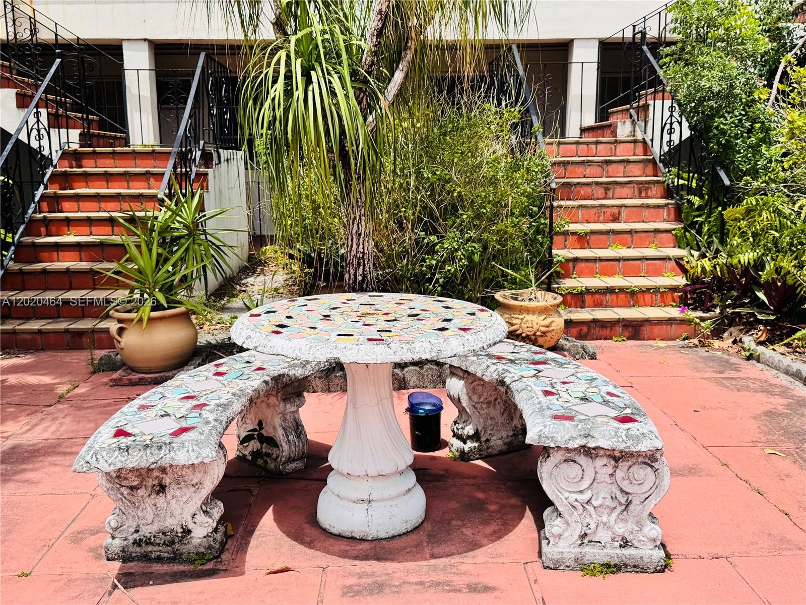 A mosaic-tiled stone table and curved benches sit on a patio between two staircases — 756 N 17th Ave # 15, Hollywood FL 33020, HOLLYWOOD, FL