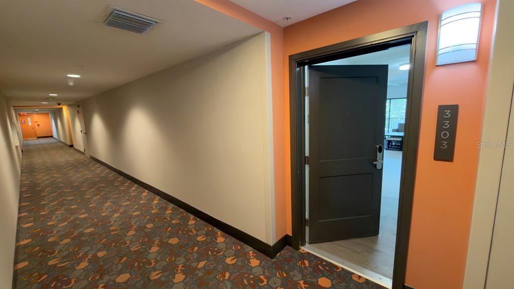 A hallway with patterned carpet leads to an open apartment door labeled 3303 — 14501 GROVE RESORT AVENUE UNIT 3303, WINTER GARDEN, FL