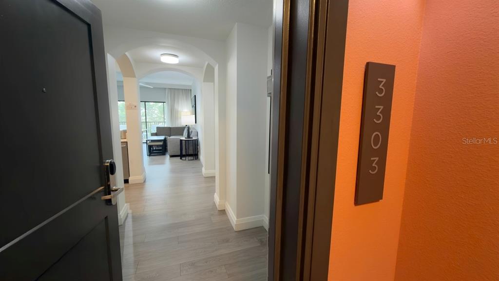 An open door reveals a hallway leading into a living area with light wood flooring — 14501 GROVE RESORT AVENUE UNIT 3303, WINTER GARDEN, FL
