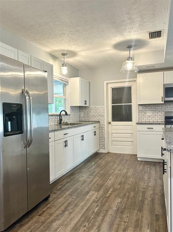 A kitchen features white cabinets, granite countertops, a subway tile backsplash, and stainless steel appliances — 5936 ELM STREET, NEW PORT RICHEY, FL