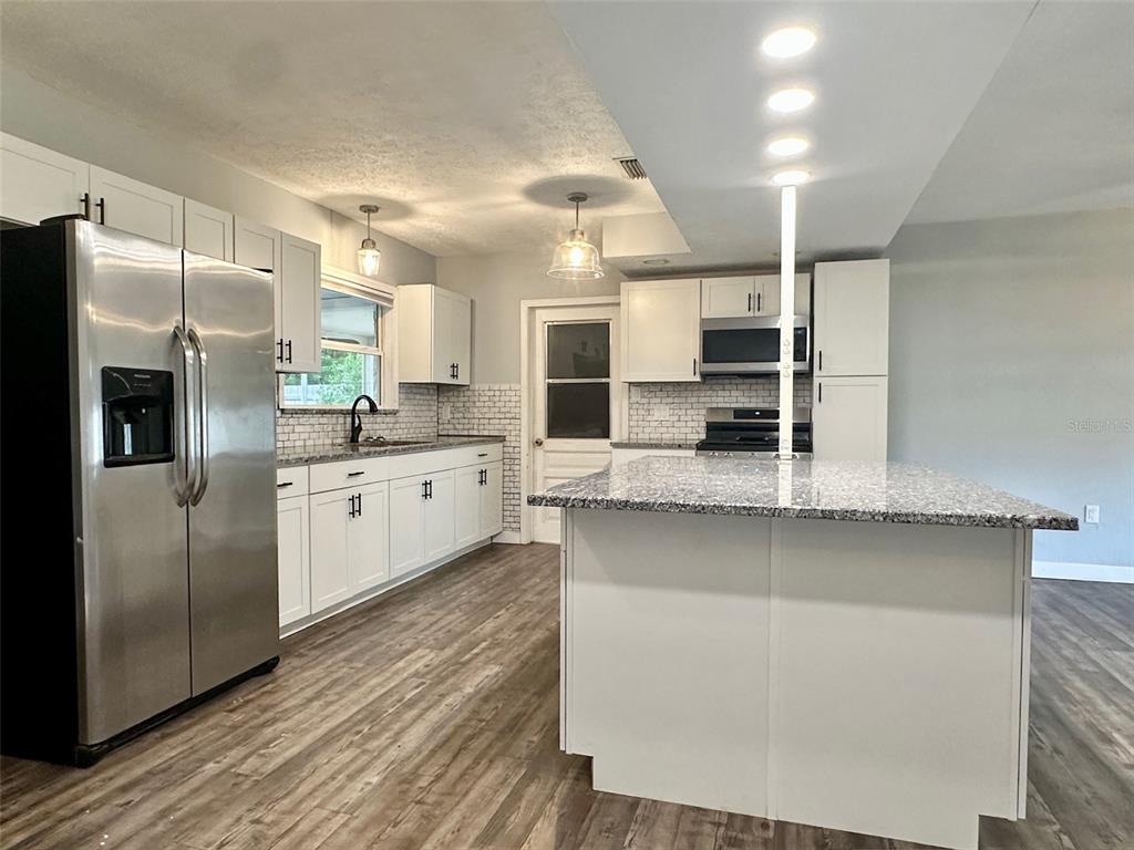 A kitchen features white cabinets, granite countertops, stainless steel appliances, and a central island — 5936 ELM STREET, NEW PORT RICHEY, FL