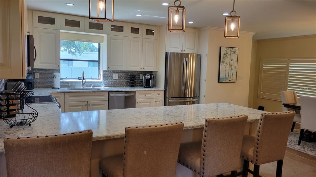 A kitchen features white cabinetry, granite countertops, stainless steel appliances, and a breakfast bar — 3932 SUNSHINE AVENUE, SARASOTA, FL