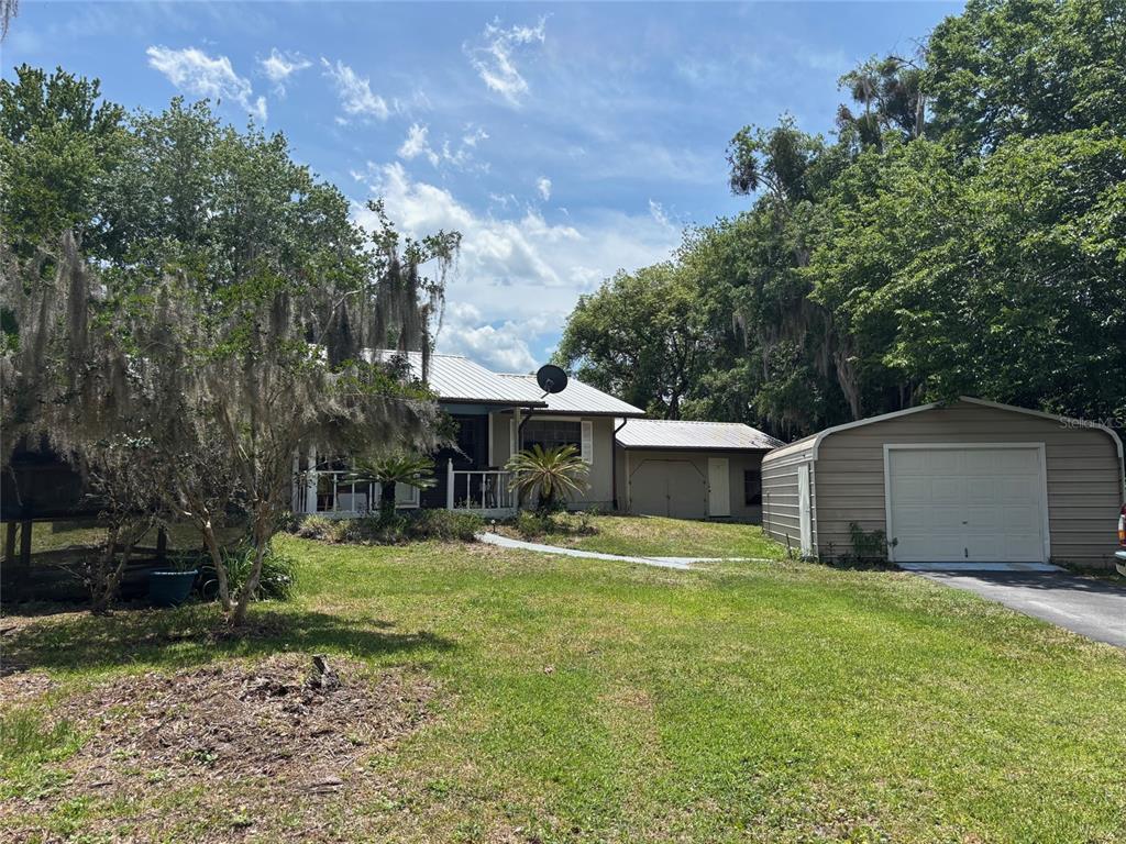 A single-story house with a metal roof and a detached metal garage in a yard — 333 RIVIERA DRIVE, CRESCENT CITY, FL